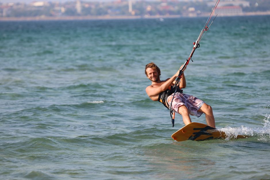 A man kiteboarding on the sea during a sunny summer day, capturing the thrill of water sports.