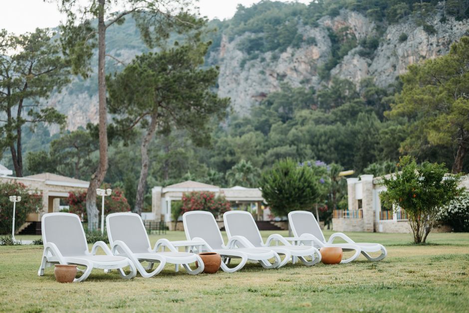 Peaceful resort garden with sunbeds and lush mountain backdrop, ideal for relaxation.