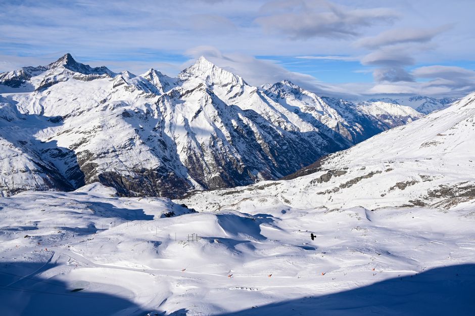 Breathtaking view of snowcapped mountains in the Alps with blue skies and rugged terrain.