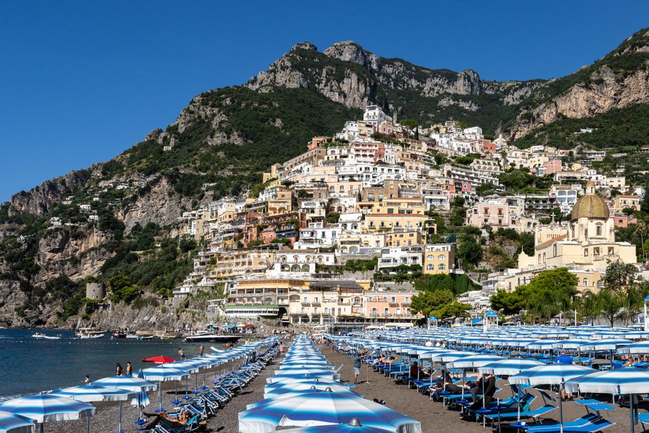 Picturesque Positano beach with colorful umbrellas and stunning hillside view in Italy.