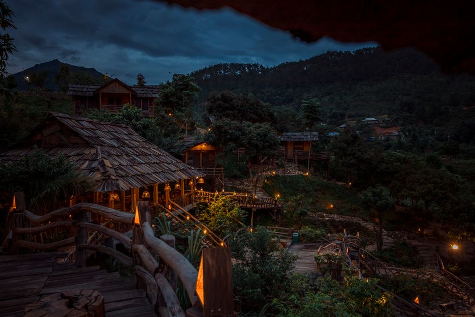 Explore the tranquility of a tropical wooden resort illuminated at night amidst lush greenery.