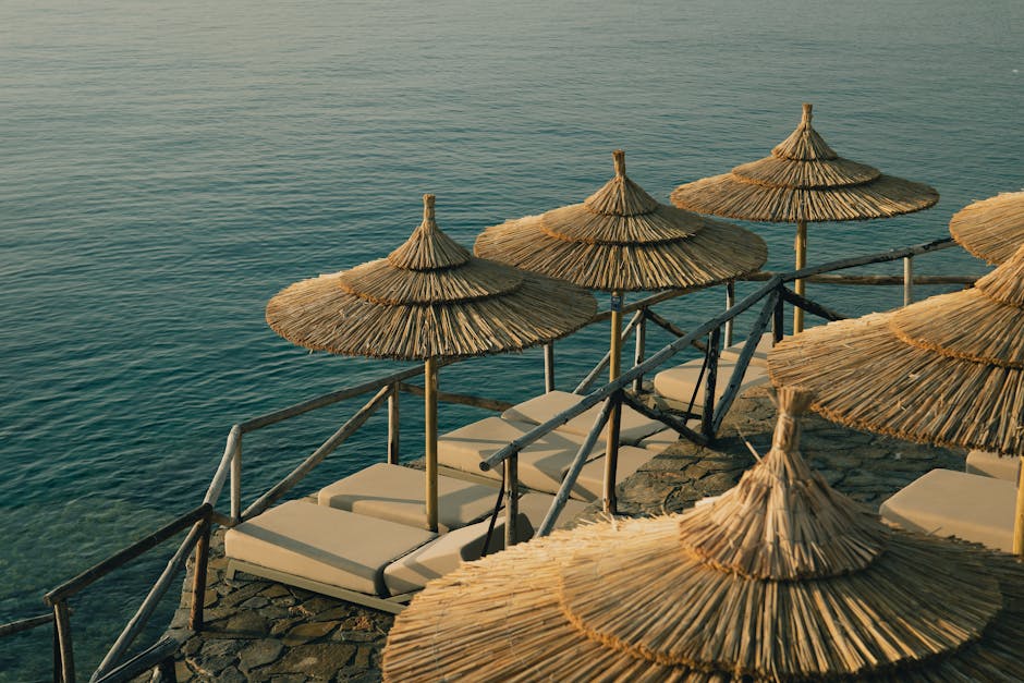 Relaxing beachside view with straw umbrellas and sunbeds by the sea, perfect for a summer getaway.