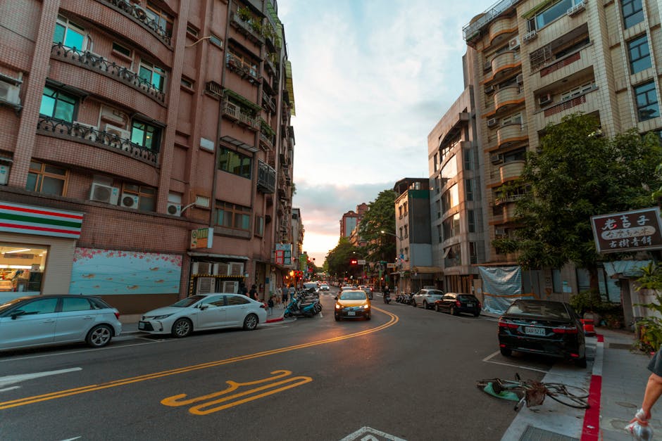 A vibrant city street with cars and buildings at sunset, showcasing urban life.