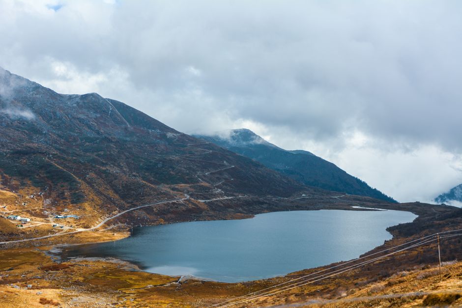A breathtaking aerial view of a tranquil mountain lake surrounded by rugged terrains and cloudy skies, perfect for nature enthusiasts.