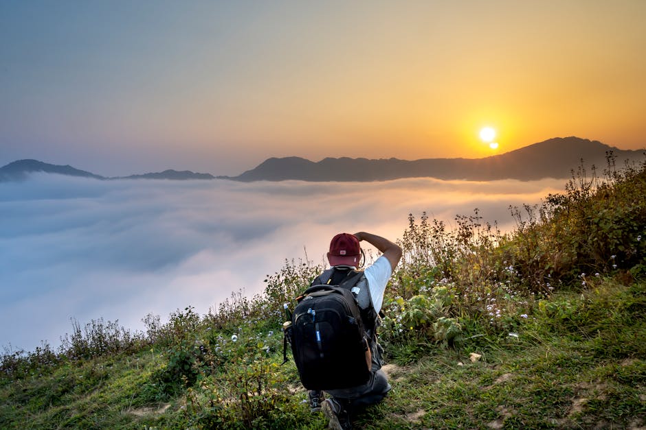 A photographer kneels to capture a stunning sunrise over misty mountains.