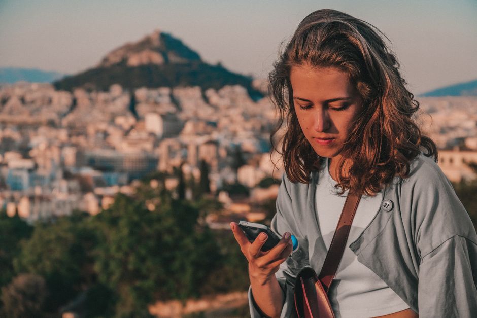 Young woman using a smartphone with Athens, Greece as the backdrop.