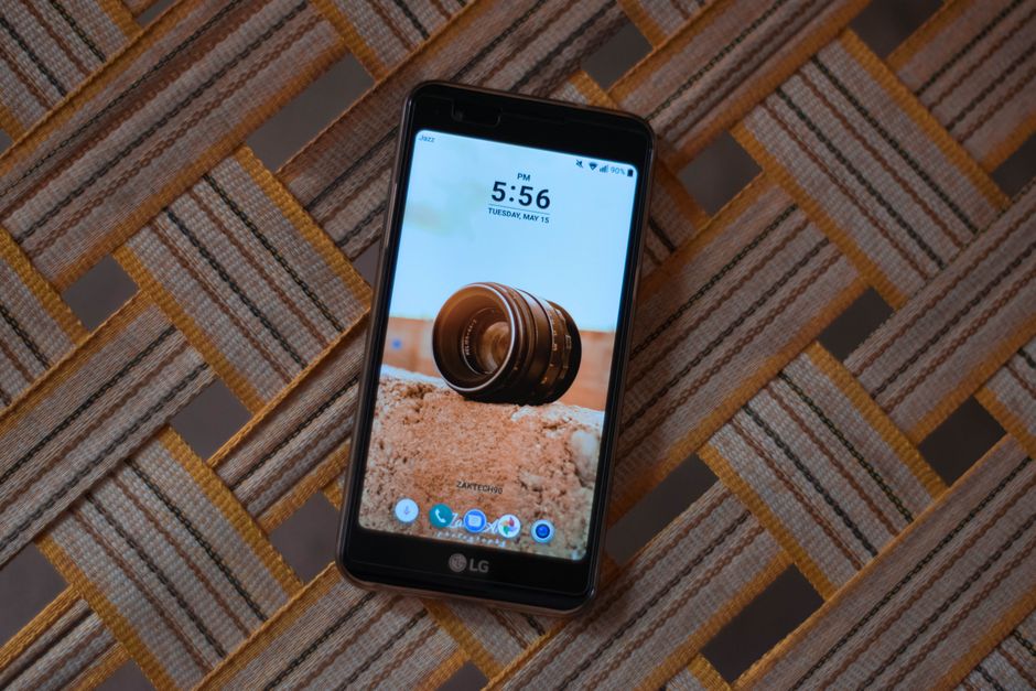 An LG smartphone displaying time on a textured table surface.