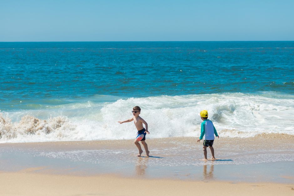 Two young boys play by the ocean's edge, enjoying a sunny summer day at the beach.
