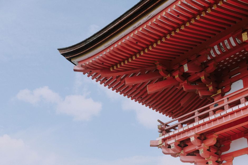 Close-up of a red Japanese temple roof against a blue sky in Kyoto, Japan.