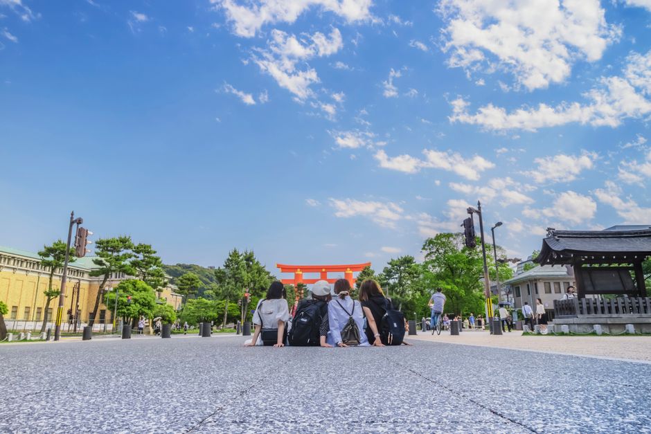 A group of young women enjoying a sunny day near a torii gate in Kyoto, Japan.