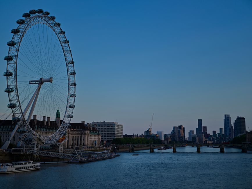 View of the London Eye and city skyline during dusk over the River Thames in London.