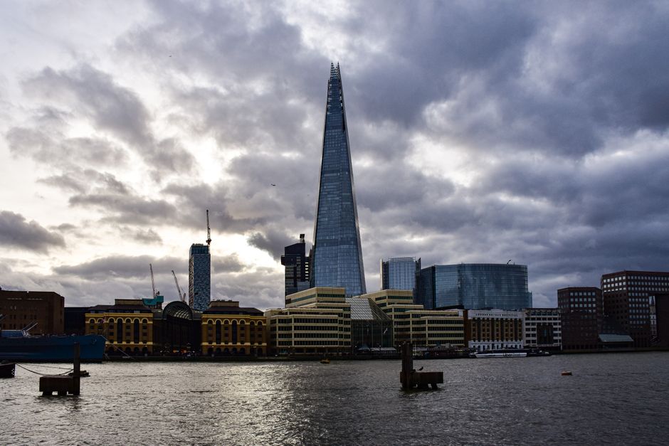 Dramatic view of The Shard and the London skyline under moody clouds.