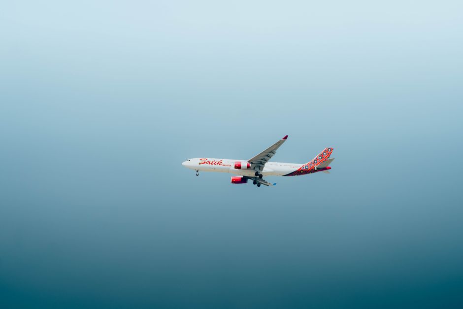 Commercial airplane flying through a clear blue sky, mid-flight view against a cloudless backdrop.