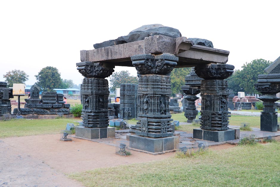 Intricate stone pillar ruins outdoors, showcasing detailed carvings and historic architecture.