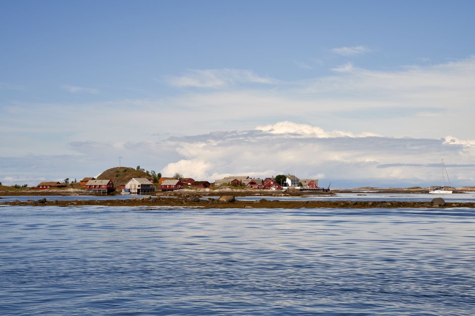 Picturesque view of a waterfront village with red houses by a serene sea under a clear sky.