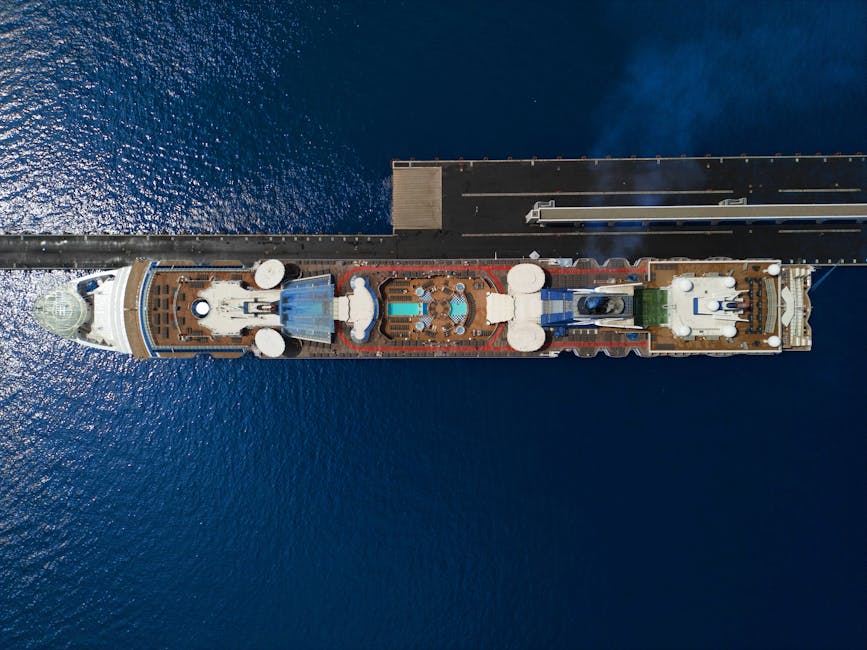 Top view of a luxury cruise ship with pool docked at a pier in the ocean.