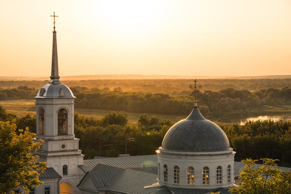 Serene sunset view over a historic church dome amidst lush greenery.