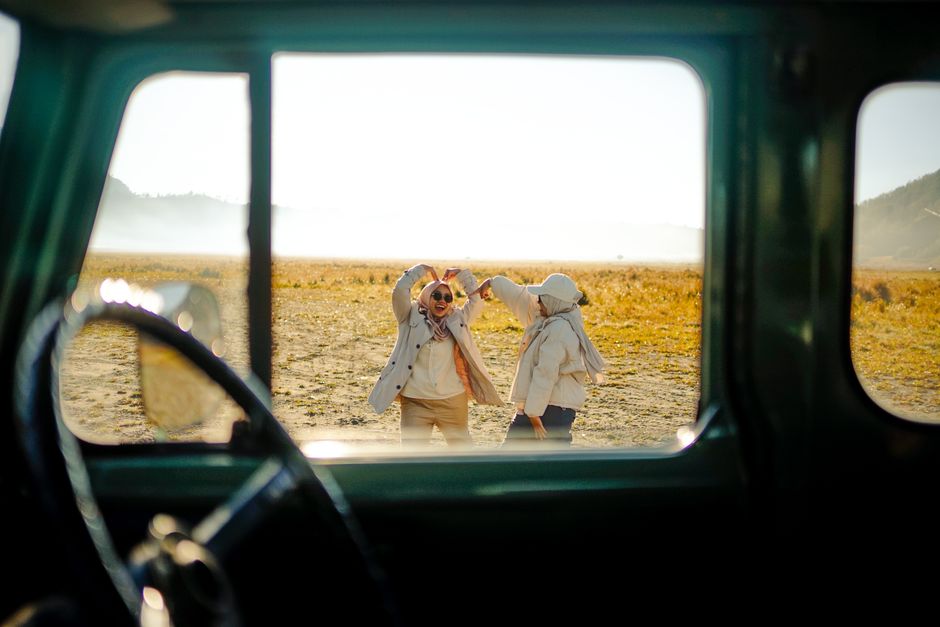 Two friends enjoying a fun road trip, dancing near Mount Bromo in East Java, Indonesia.