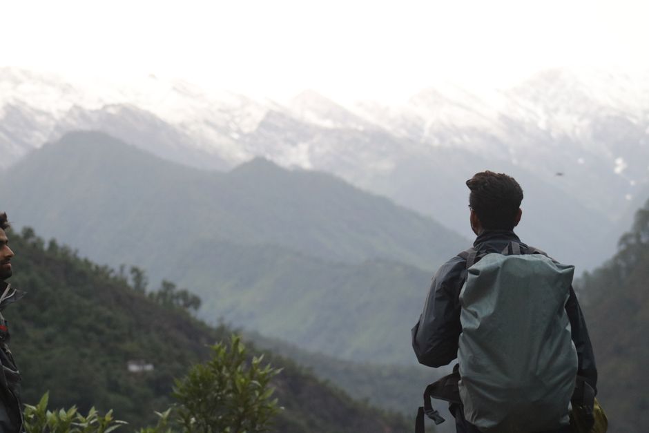 A hiker enjoys a peaceful view of the snow-capped mountains in Wadgaon, India.