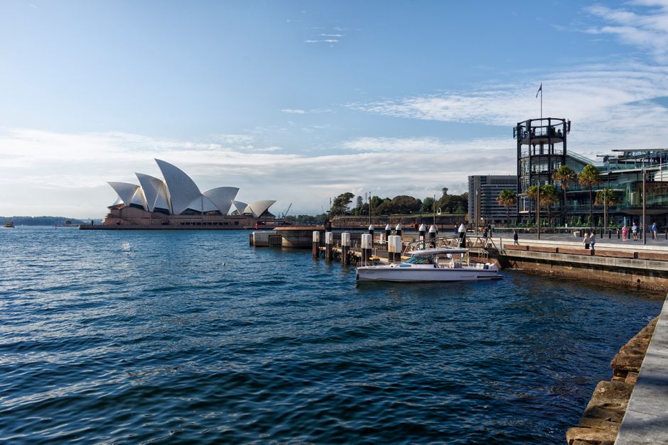 Scenic view of the Sydney Opera House and harbor with clear skies and reflections.