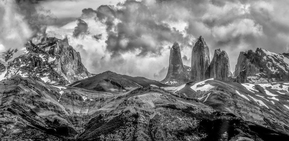 Monochrome view of Torres del Paine peaks under a dramatic cloudy sky.