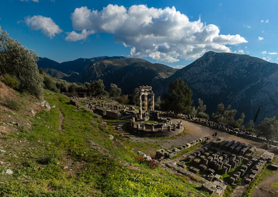Explore the ancient ruins of Delphi, Greece, set against a stunning mountain landscape under a vibrant blue sky.