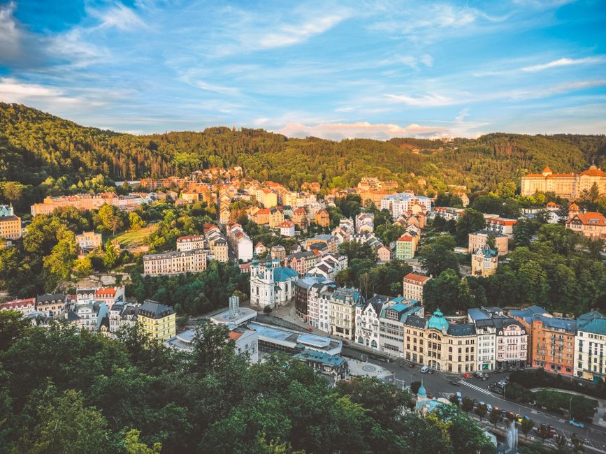 Aerial view of a European town nestled among lush green hills with colorful architecture.