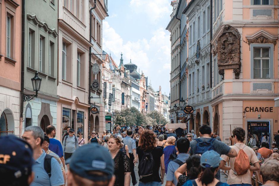 Crowded street in Prague showcasing historic architecture with tourists walking under a blue sky.