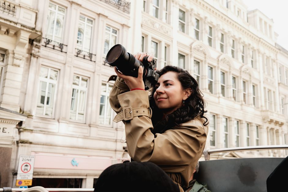 A woman with a camera capturing city architecture outdoors.