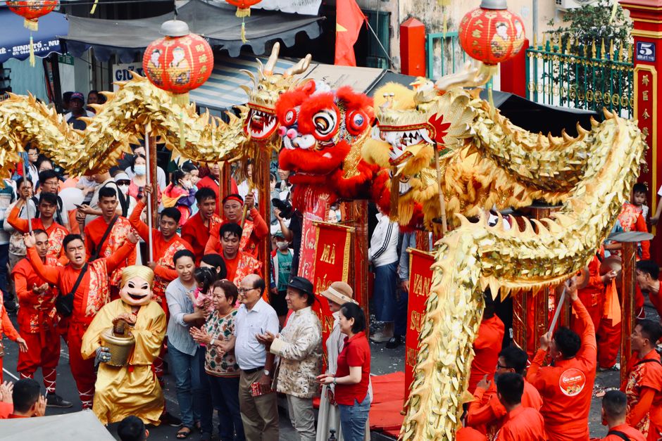 Colorful dragon dance at a bustling street festival with vibrant costumes.