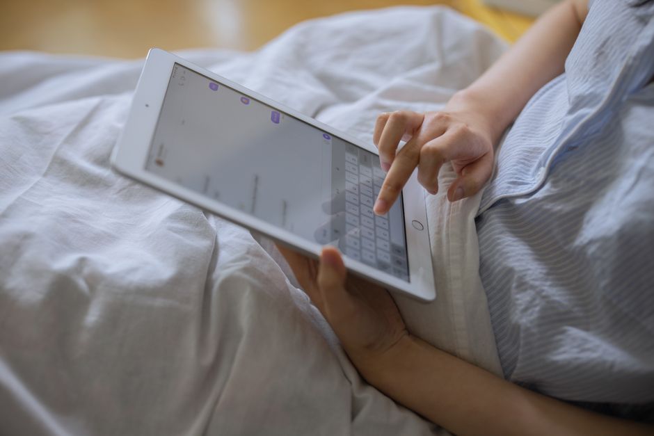 A person comfortably using a digital tablet indoors, typing on a virtual keyboard.
