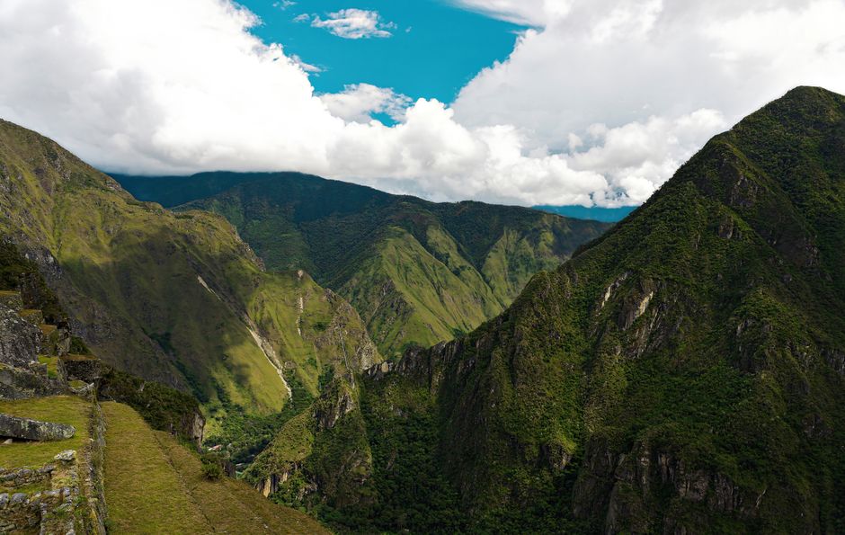 Stunning view of the lush Andes mountains under a bright blue sky with scattered clouds.